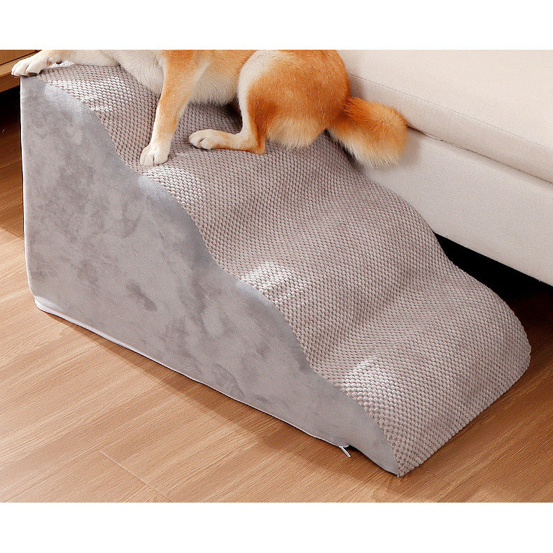 Dog resting on gray pet stairs beside a sofa