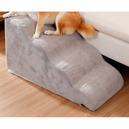 Dog resting on gray pet stairs beside a sofa